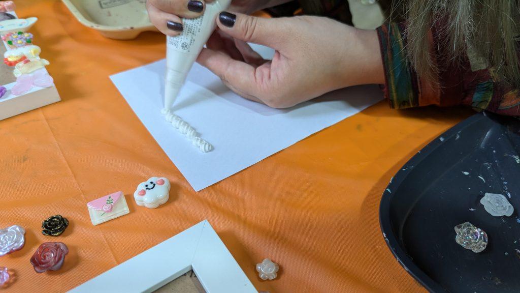 a woman sitting at a table working on a craft project