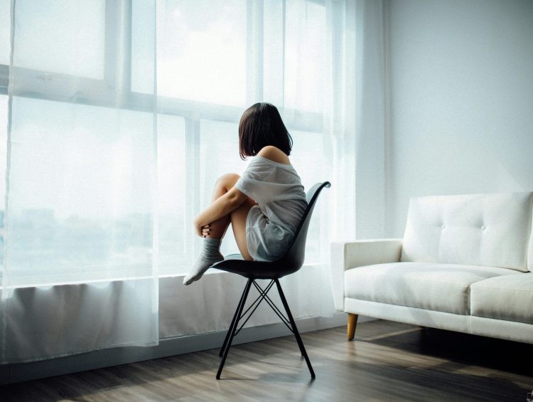 a woman sitting on a chair in front of a window