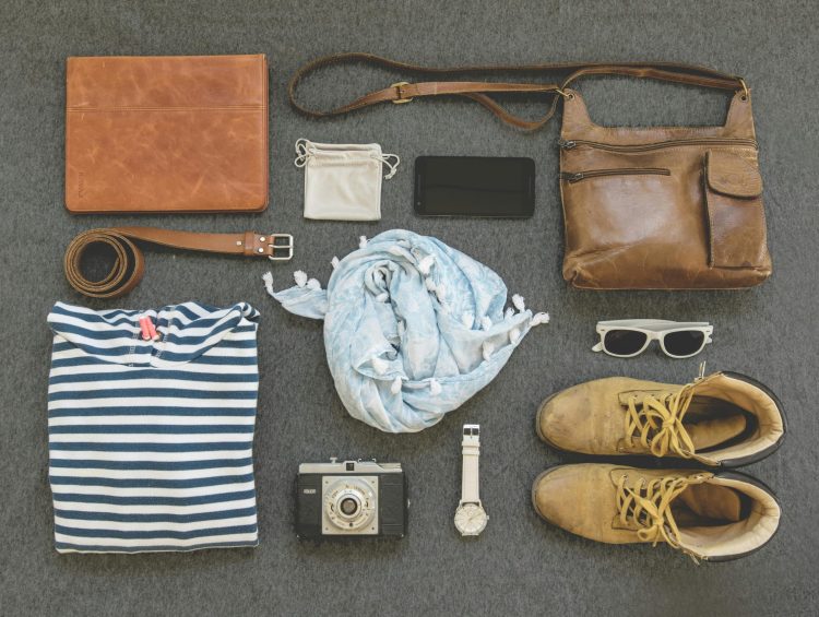 An assortment of items featuring a camera, sunglasses, a wallet, and shoes, all positioned together for visual interest.
