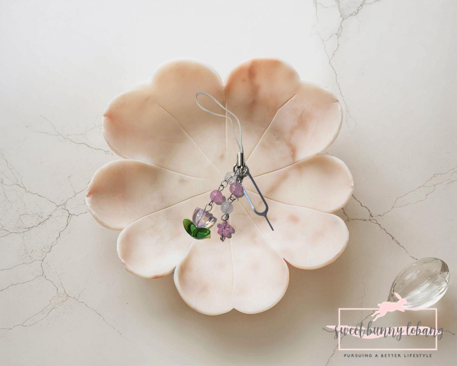 A pink flower with a green stem and wire, symbolizing a Pin Charm for SIM card removal.