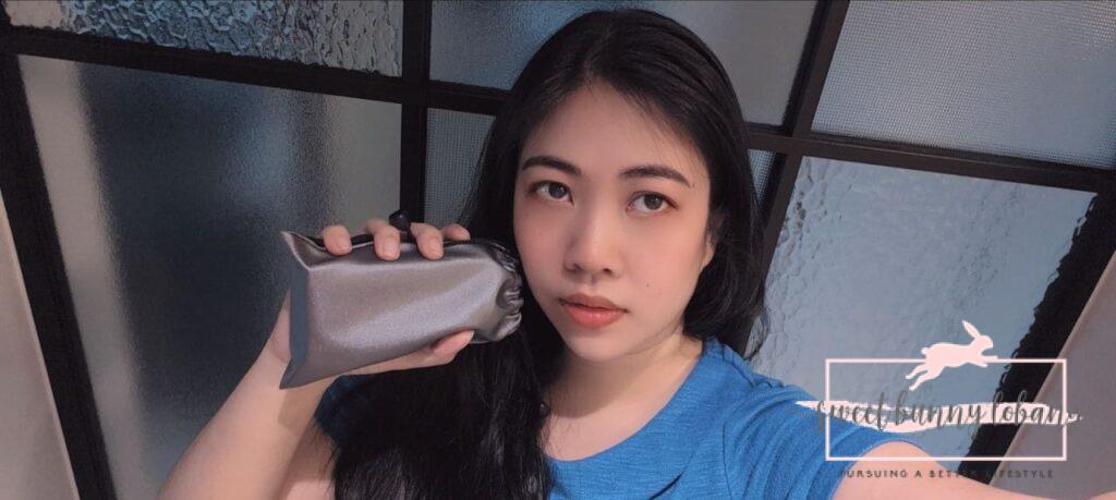  A woman with a silver camera pouch takes a selfie, capturing her joyful expression.